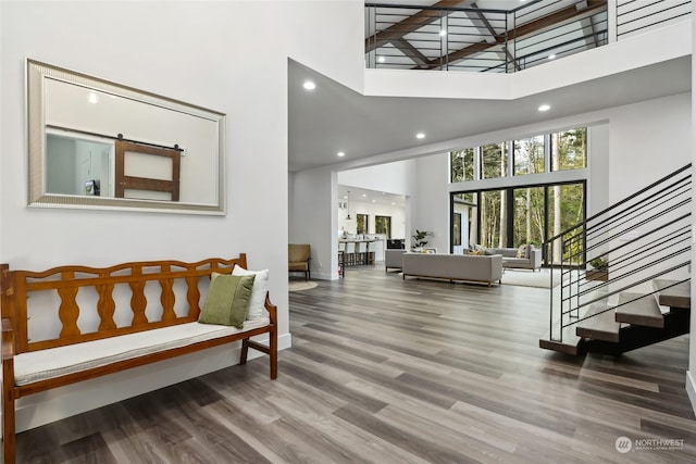 interior space with a high ceiling, a barn door, and wood-type flooring