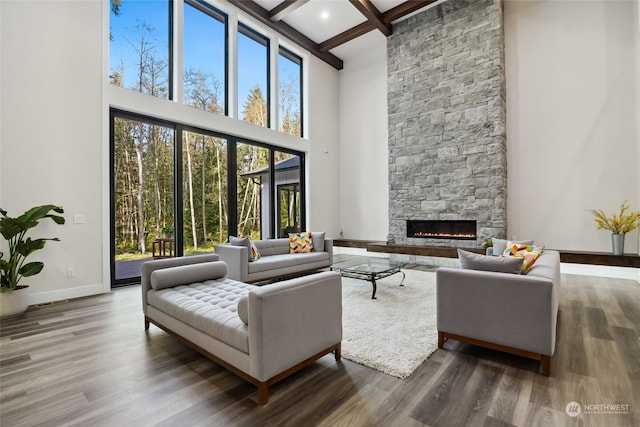 living room featuring beamed ceiling, a fireplace, hardwood / wood-style flooring, and plenty of natural light