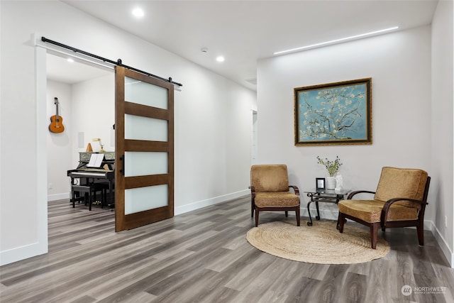 sitting room featuring wood-type flooring and a barn door