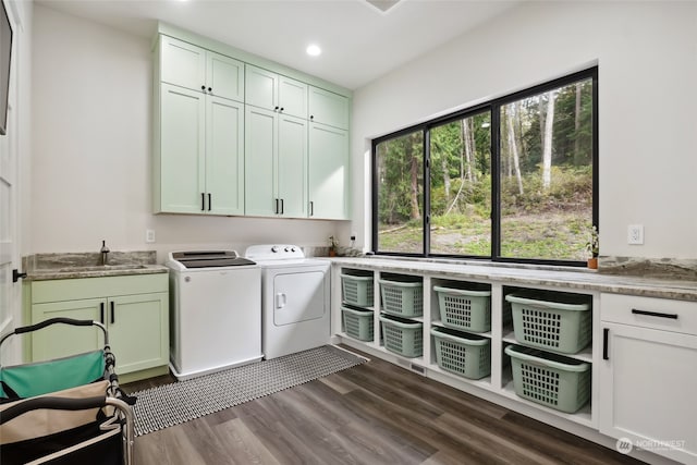 clothes washing area featuring sink, washing machine and dryer, dark hardwood / wood-style floors, and cabinets