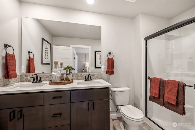 bathroom featuring a shower with door, vanity, decorative backsplash, and toilet