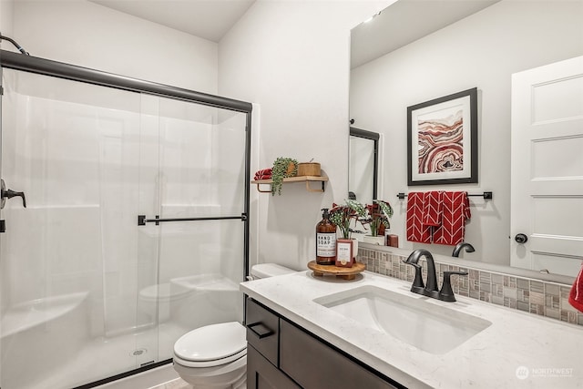 bathroom featuring vanity, toilet, a shower with shower door, and backsplash