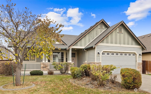 craftsman-style home with covered porch, a front yard, and a garage