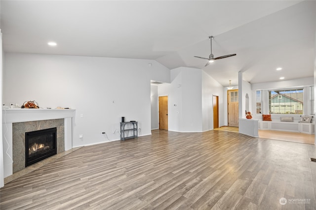 unfurnished living room with vaulted ceiling, light hardwood / wood-style flooring, a tile fireplace, and ceiling fan