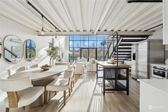 dining space with a wall mounted AC and hardwood / wood-style flooring