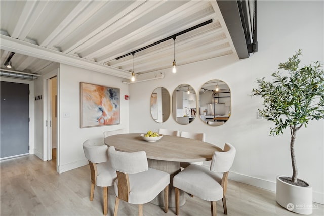 dining room with beamed ceiling and light wood-type flooring