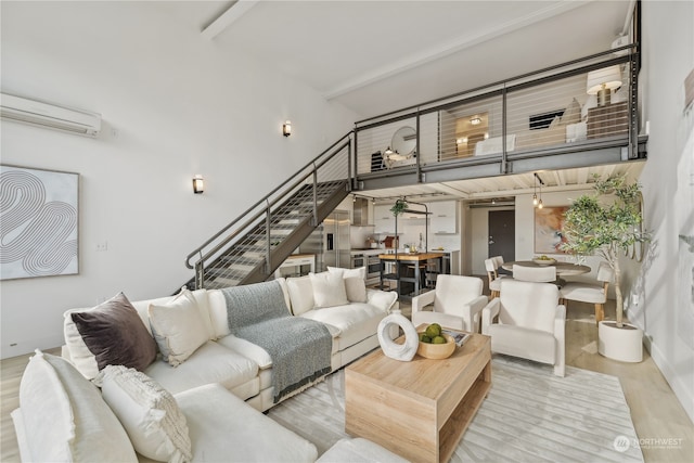 living room featuring light wood-type flooring, a wall mounted AC, and a towering ceiling