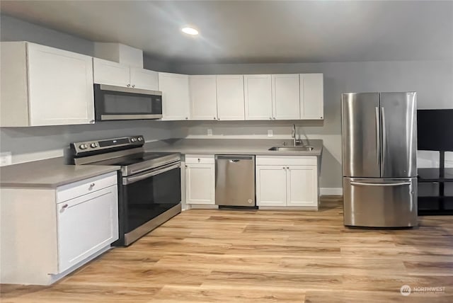 kitchen with white cabinets, appliances with stainless steel finishes, sink, and light hardwood / wood-style flooring