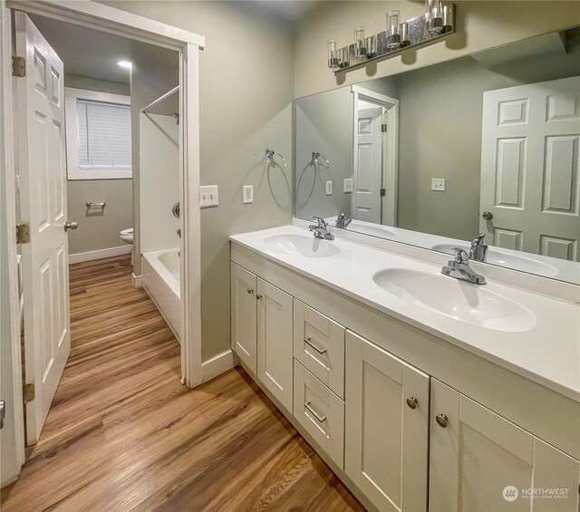 full bathroom featuring hardwood / wood-style floors, vanity, bathing tub / shower combination, and toilet