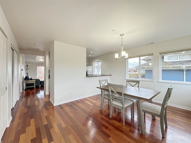 dining area with dark wood-type flooring and an inviting chandelier