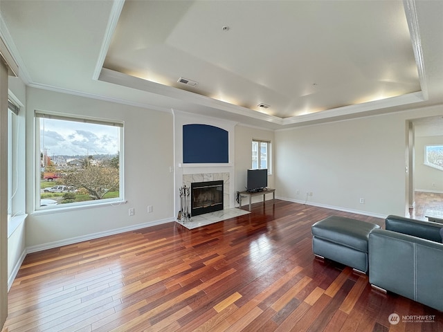 living room with hardwood / wood-style flooring, a premium fireplace, crown molding, and a tray ceiling