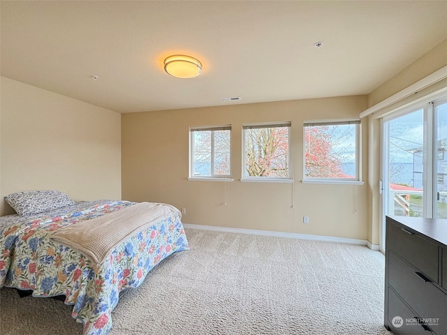 bedroom with multiple windows and light carpet