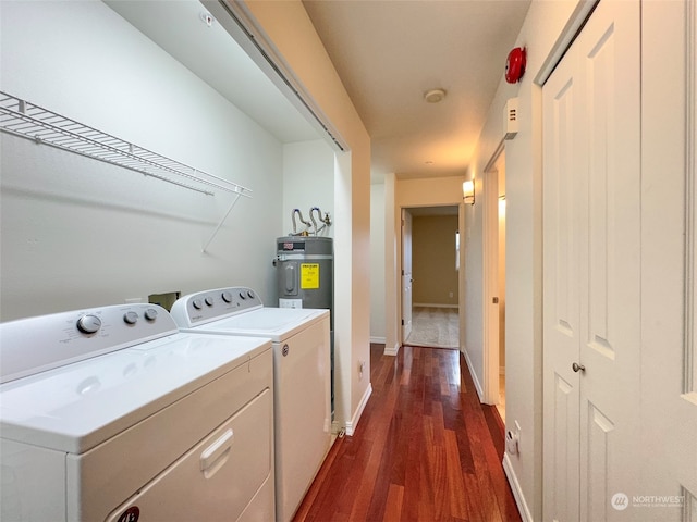 clothes washing area with dark hardwood / wood-style flooring, strapped water heater, and washing machine and clothes dryer