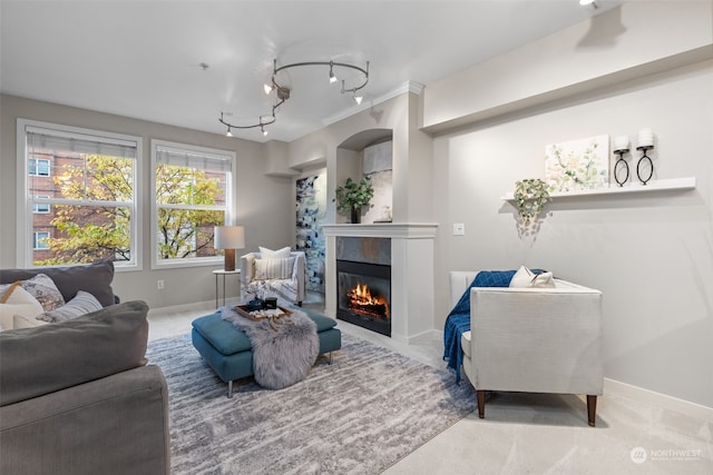 carpeted living room with rail lighting and ornamental molding