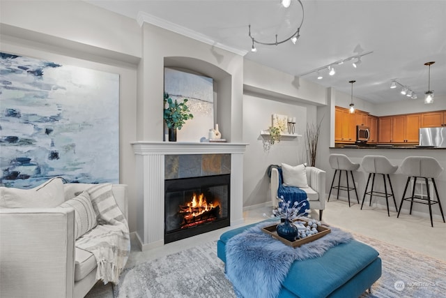 living room with ornamental molding, a tiled fireplace, and track lighting