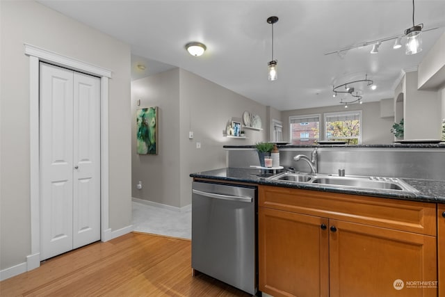 kitchen featuring light hardwood / wood-style flooring, hanging light fixtures, dark stone counters, sink, and stainless steel dishwasher