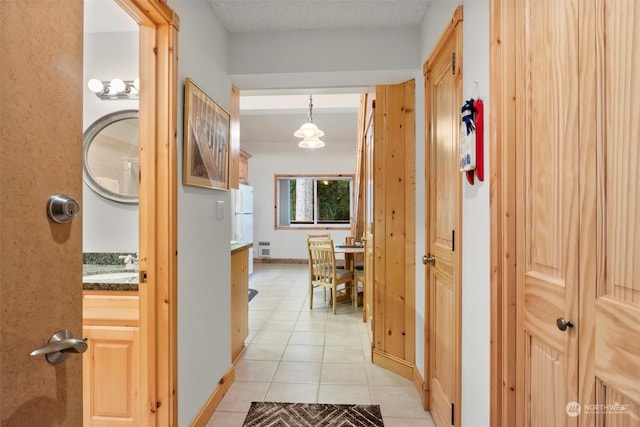 hallway with sink, light tile patterned flooring, and a textured ceiling