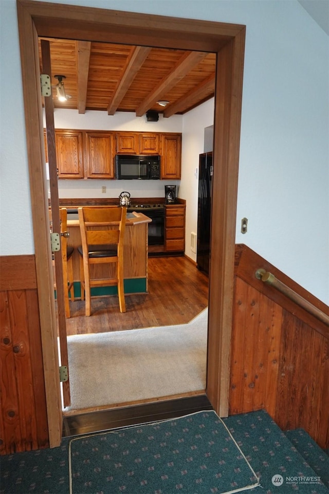 1399 Ocean Shores Blvd SW Unit 2N-E, Ocean Shores, WA 98569 - kitchen featuring black appliances, a wooden ceiling with exposed beams, brown cabinets, and wood finished floors