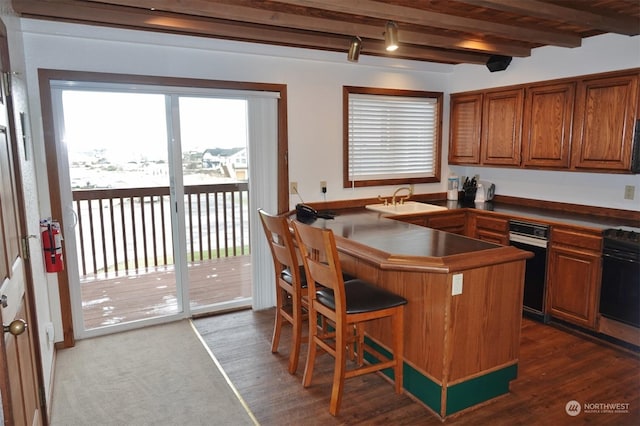1399 Ocean Shores Blvd SW Unit 2N-E, Ocean Shores, WA 98569 - kitchen with brown cabinetry, beam ceiling, dark countertops, a breakfast bar, and dark wood-style floors