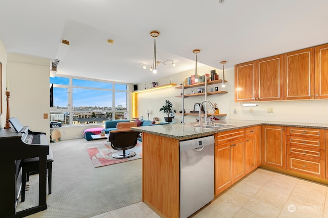 kitchen featuring kitchen peninsula, hanging light fixtures, light stone counters, stainless steel dishwasher, and sink