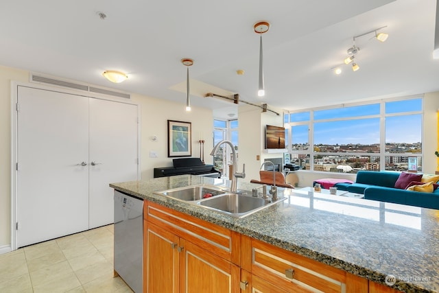 kitchen with sink, hanging light fixtures, stainless steel dishwasher, dark stone countertops, and light tile patterned floors