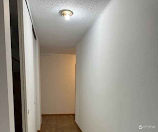 hallway with hardwood / wood-style floors and a textured ceiling