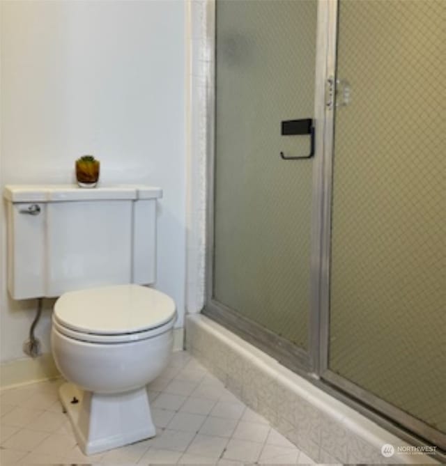 bathroom featuring tile patterned floors, a shower with door, and toilet