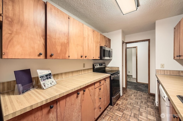 kitchen featuring dark parquet flooring, butcher block counters, stainless steel appliances, and a textured ceiling