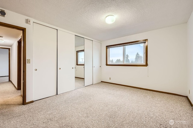 unfurnished bedroom featuring carpet flooring, a textured ceiling, and a closet