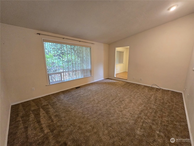 carpeted spare room with a textured ceiling and vaulted ceiling