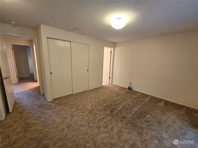 unfurnished bedroom featuring a closet, a textured ceiling, and dark colored carpet