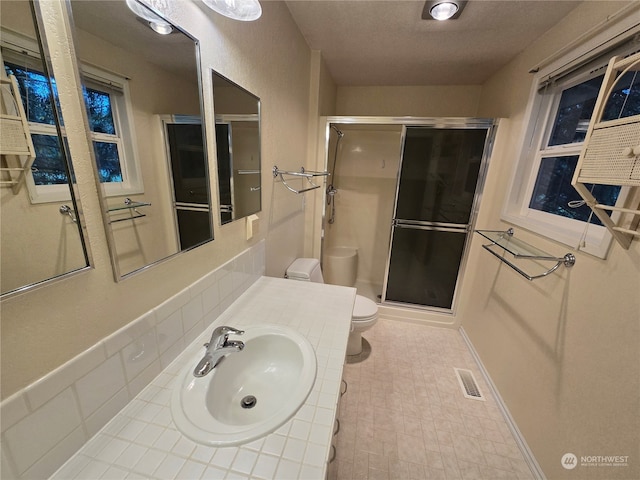 bathroom featuring toilet, a shower with shower door, and vanity