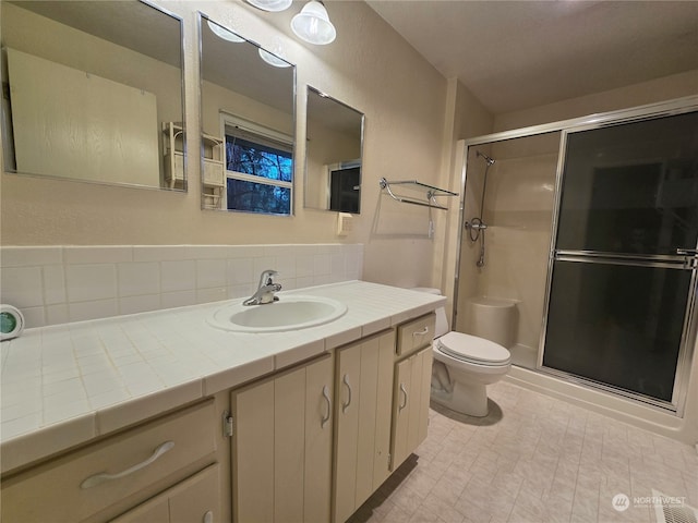 bathroom with toilet, vanity, and a shower with door