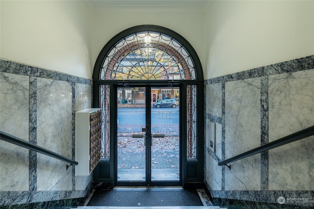 foyer featuring tile walls, crown molding, and french doors