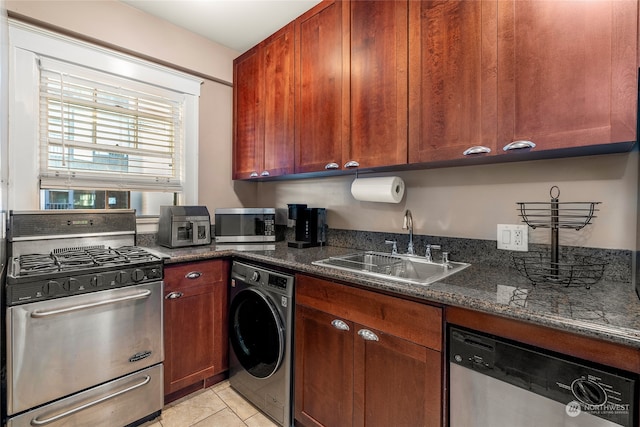 kitchen featuring washer / clothes dryer, stainless steel appliances, dark stone counters, sink, and light tile patterned floors