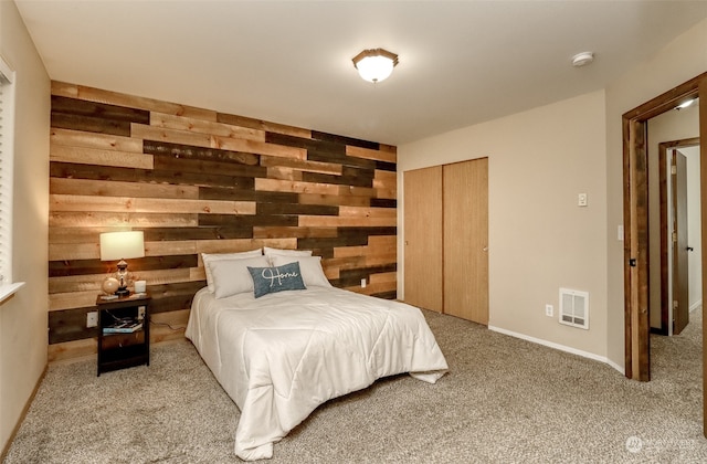 bedroom with a closet, light carpet, and wooden walls