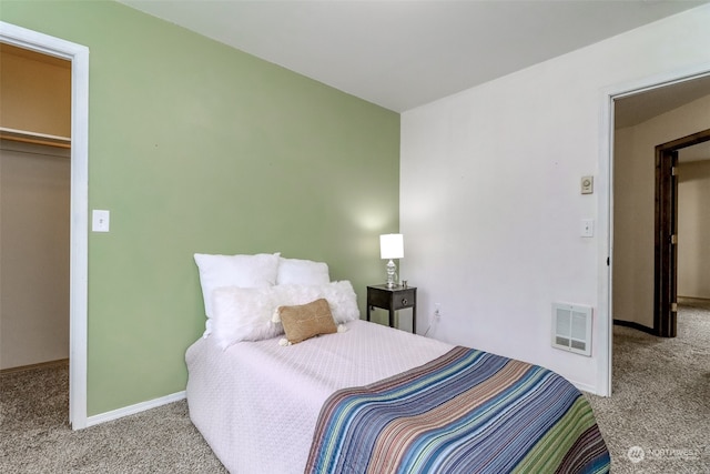 bedroom with a closet, heating unit, a walk in closet, and light colored carpet