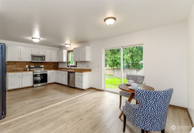 kitchen featuring white cabinets, stainless steel appliances, sink, and light wood-type flooring