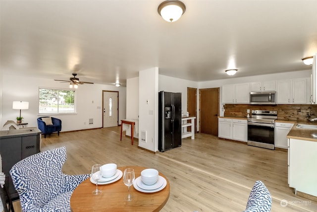 dining area featuring sink, light wood-type flooring, and ceiling fan