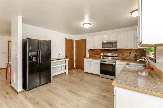 kitchen with decorative backsplash, stainless steel appliances, sink, light wood-type flooring, and white cabinetry