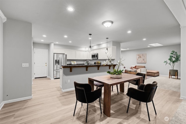 dining space featuring a skylight and light wood-type flooring