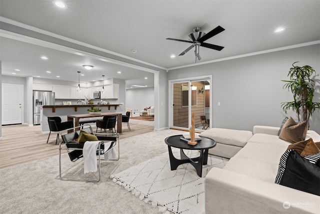 living room with ornamental molding, light hardwood / wood-style floors, and ceiling fan