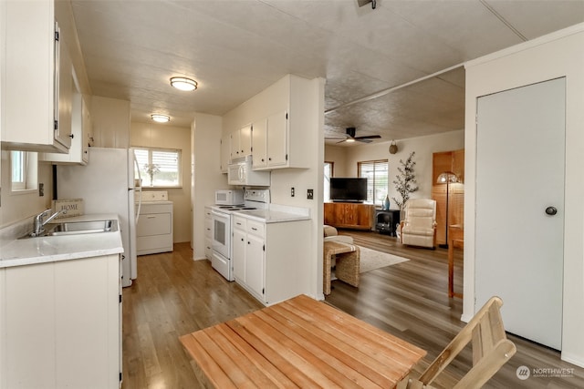 kitchen with white cabinets, washer / clothes dryer, a healthy amount of sunlight, and white appliances