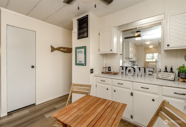 kitchen with ornamental molding, white cabinetry, hardwood / wood-style floors, and ceiling fan