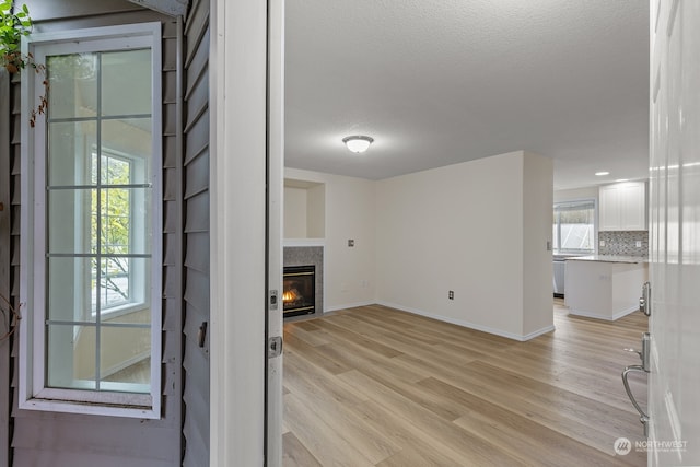 unfurnished living room with a textured ceiling and light hardwood / wood-style flooring