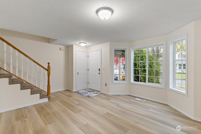 entrance foyer with a textured ceiling and light wood-type flooring