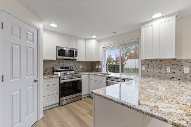 kitchen with white cabinetry, appliances with stainless steel finishes, and light stone counters