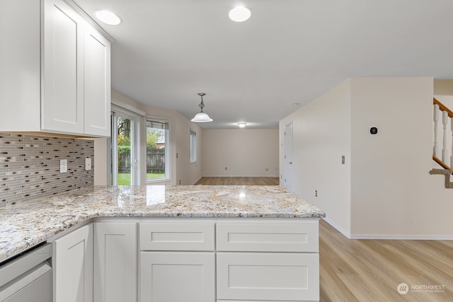 kitchen with white cabinetry, light hardwood / wood-style flooring, decorative light fixtures, and backsplash