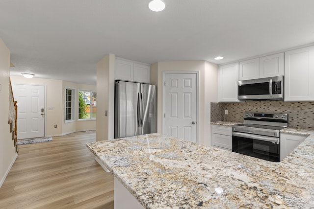 kitchen with white cabinets, stainless steel appliances, and light stone counters