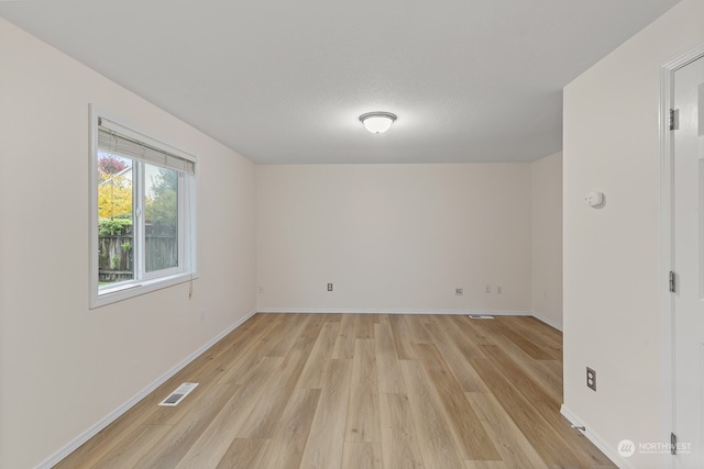 unfurnished room featuring light wood-type flooring and a textured ceiling